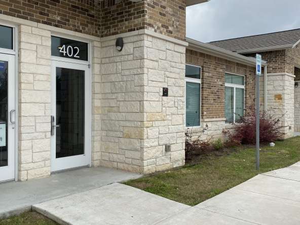 Modern hair salon storefront exterior with brick and stone accents, accessible entrance, and parking spaces.