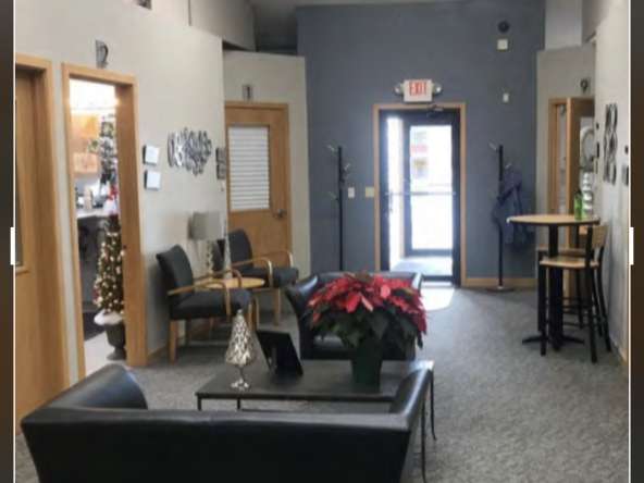 Cozy salon waiting area with black leather couches, poinsettia decorations, and wooden accents.