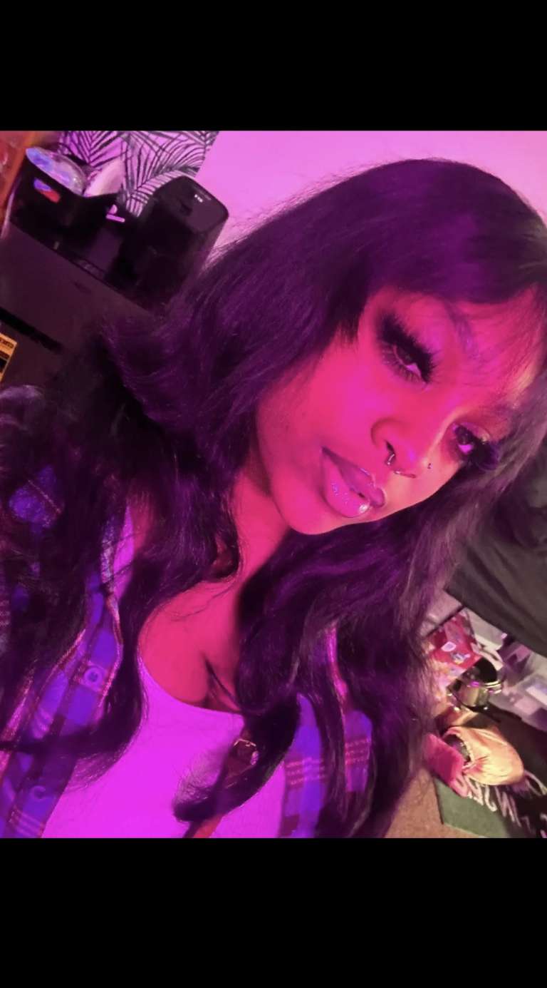 Glamorous woman with long, wavy black hair and bold makeup in a stylish salon setting.