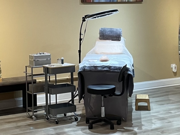 Elegant spa treatment room featuring a massage table, adjustable lighting, and organized beauty tools for relaxation services.