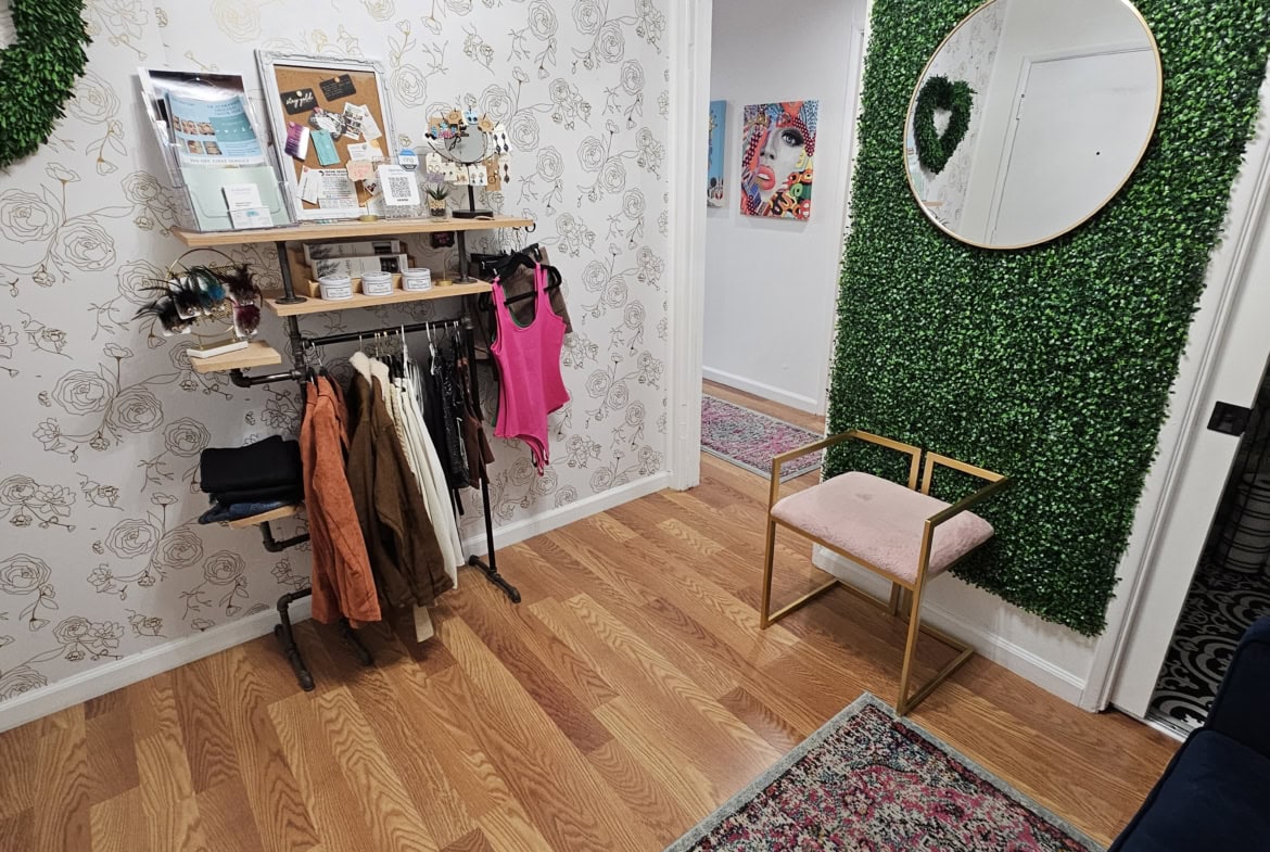 Decorative wall with greenery and floral accents at salon rental space.
