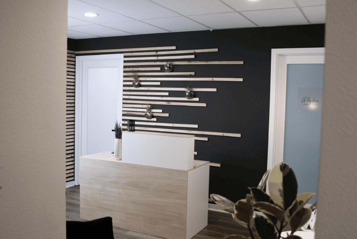 Sophisticated salon reception with modern black accent wall, wooden accents, and welcoming atmosphere.