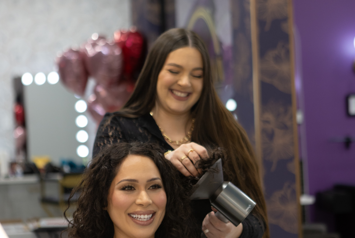 Professional hairstylist curling long, curly hair for a client.