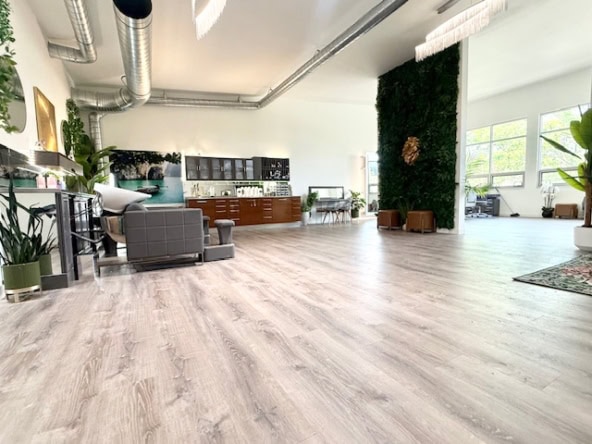 Spacious modern salon with natural light, stylish furniture, and green decor for a relaxing beauty experience.