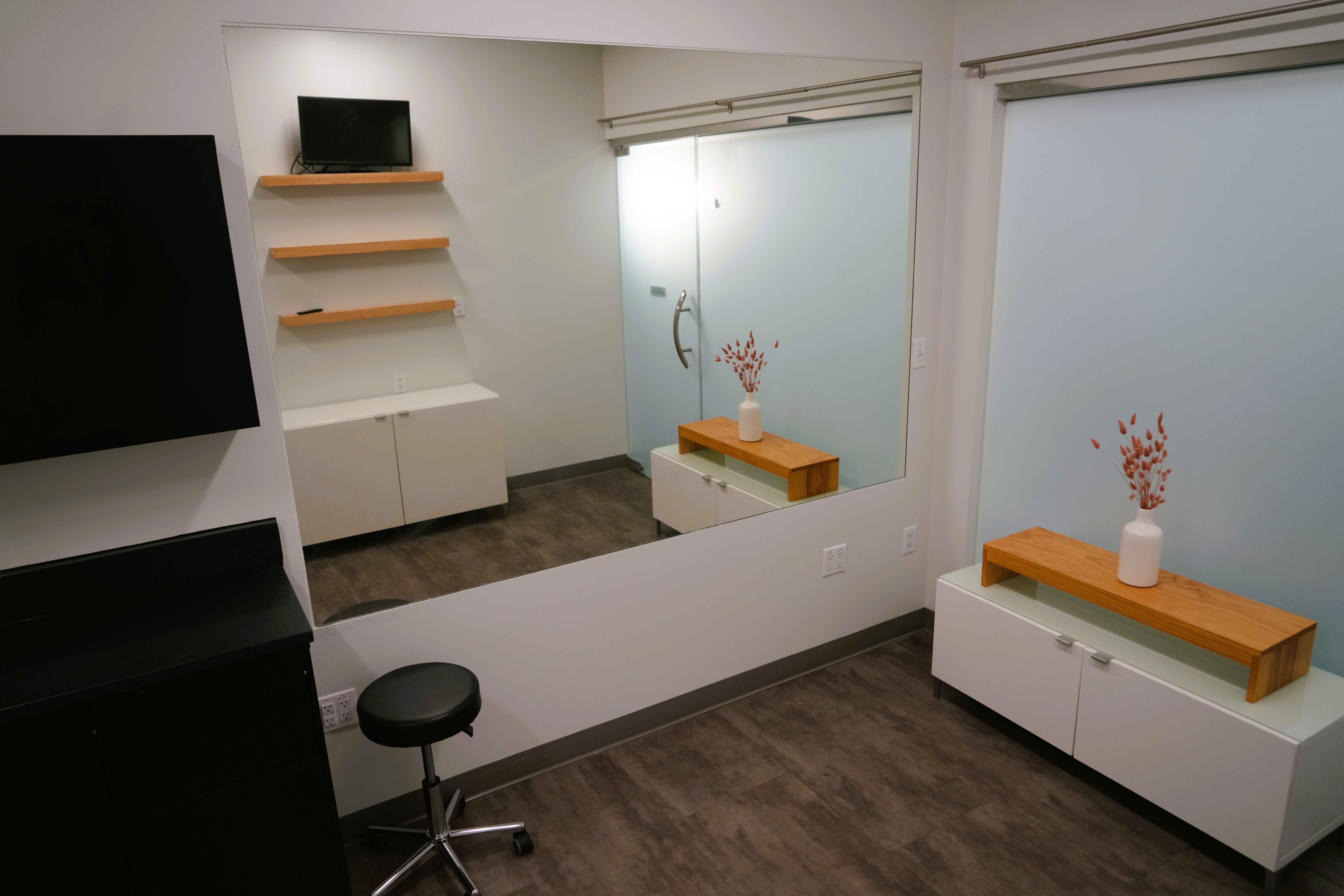 Clean, modern salon rental space featuring stylish decor, large mirror, and comfortable seating.