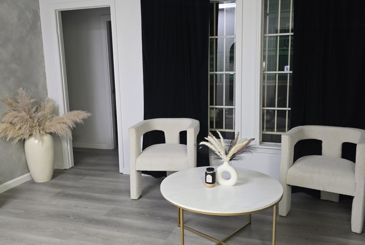 Elegant salon waiting area with two comfortable chairs, marble table, and chic decor.