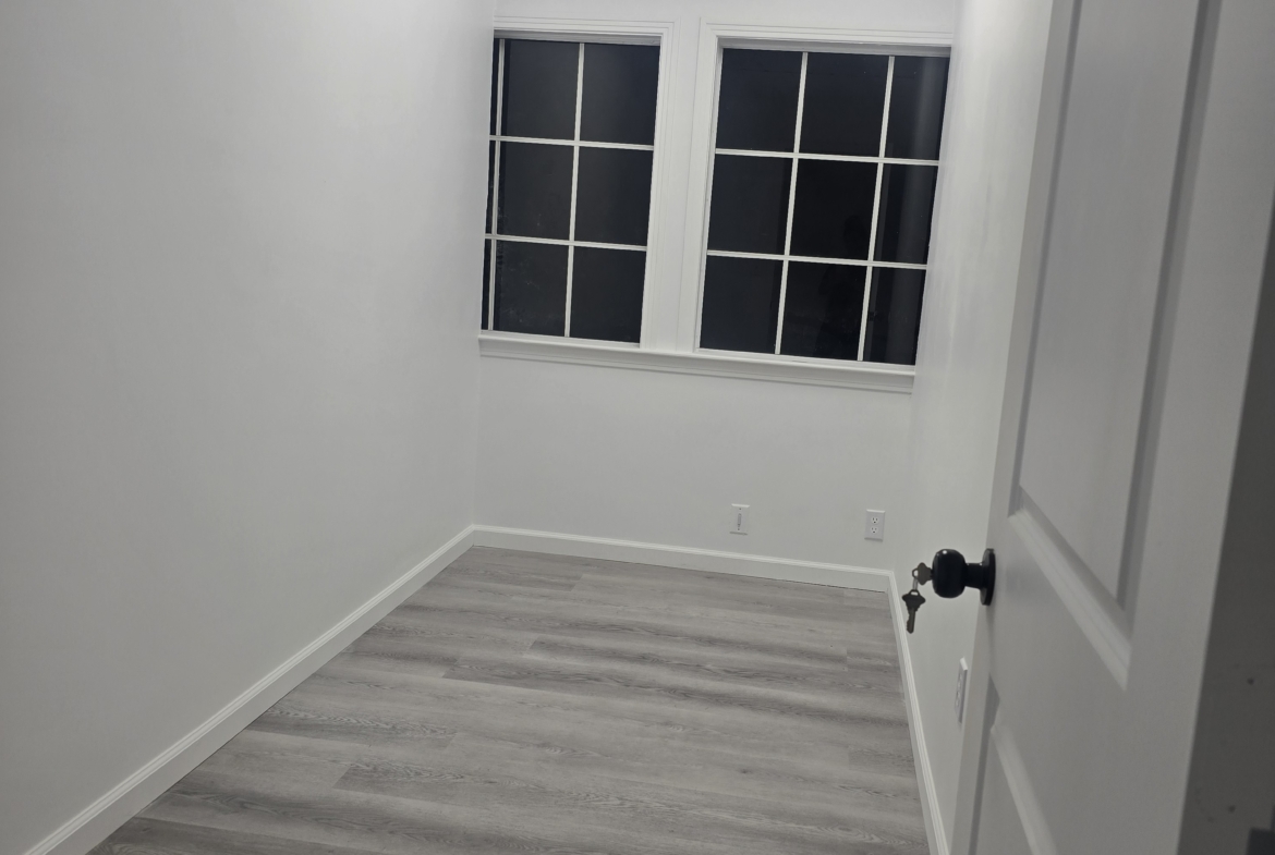 Bright, empty salon studio with hardwood floors, white walls, and ceiling light fixtures.
