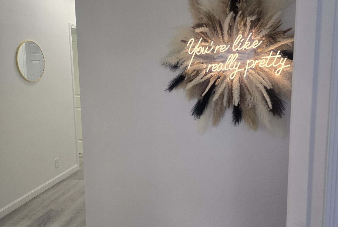 Stylish salon wall decor featuring pampas grass and neon sign with uplifting message.