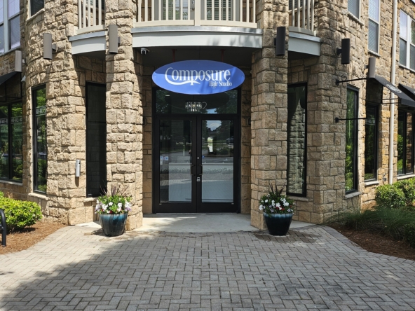 Hair salon storefront entrance with stone facade, black doors, and outdoor planters.