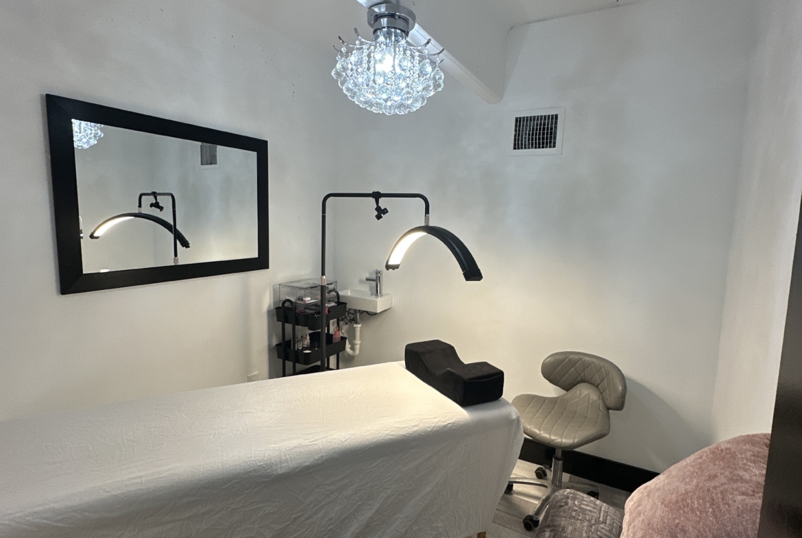 Clean, modern salon space with styling bed, lighting, and functional equipment. Perfect for beauty professionals leasing salon stations.
