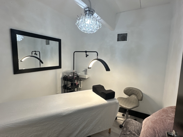 Clean, modern salon space with styling bed, lighting, and functional equipment. Perfect for beauty professionals leasing salon stations.