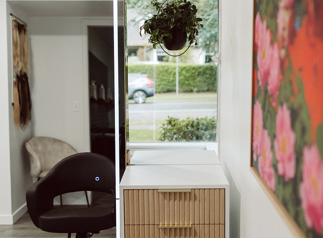 Salon reception desk with contemporary design, floral artwork, and natural light.