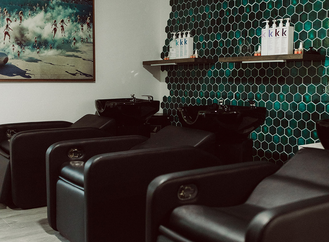 Comfortable salon shampoo chairs with black leather design and sleek interior styling.