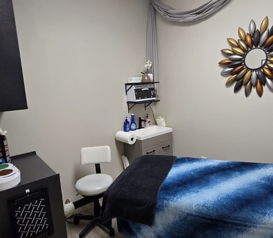 Clean salon massage room with treatment bed, decor, and professional supplies for clients.