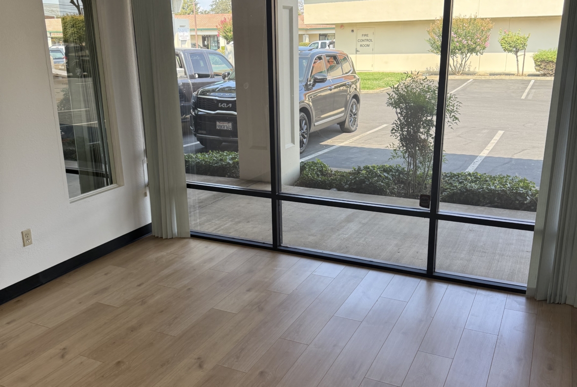 Spacious salon space with large window and wood flooring, ideal for beauty or hair salon businesses.