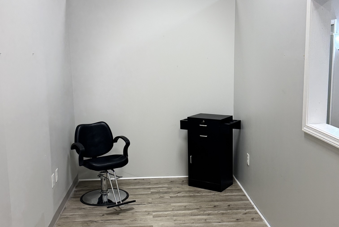Clean, empty salon rental room with chair and storage for beauty professionals.