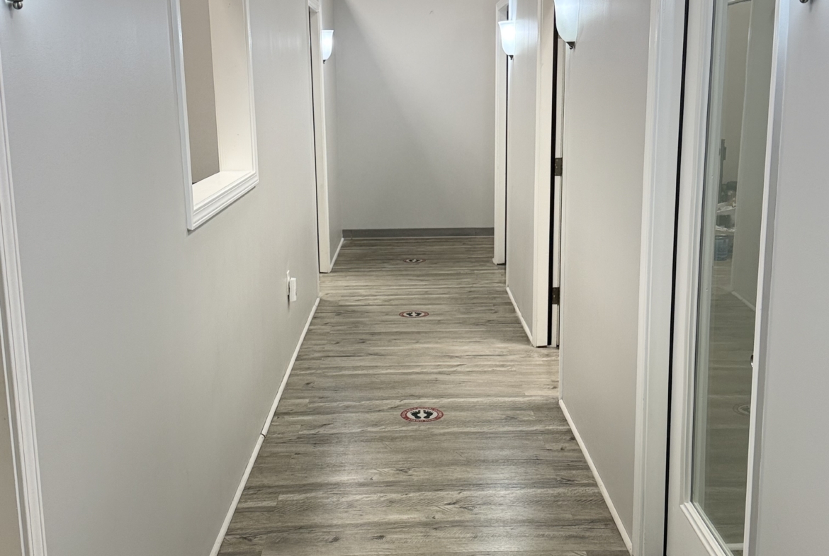 Bright salon corridor with white walls and social distancing floor signs.