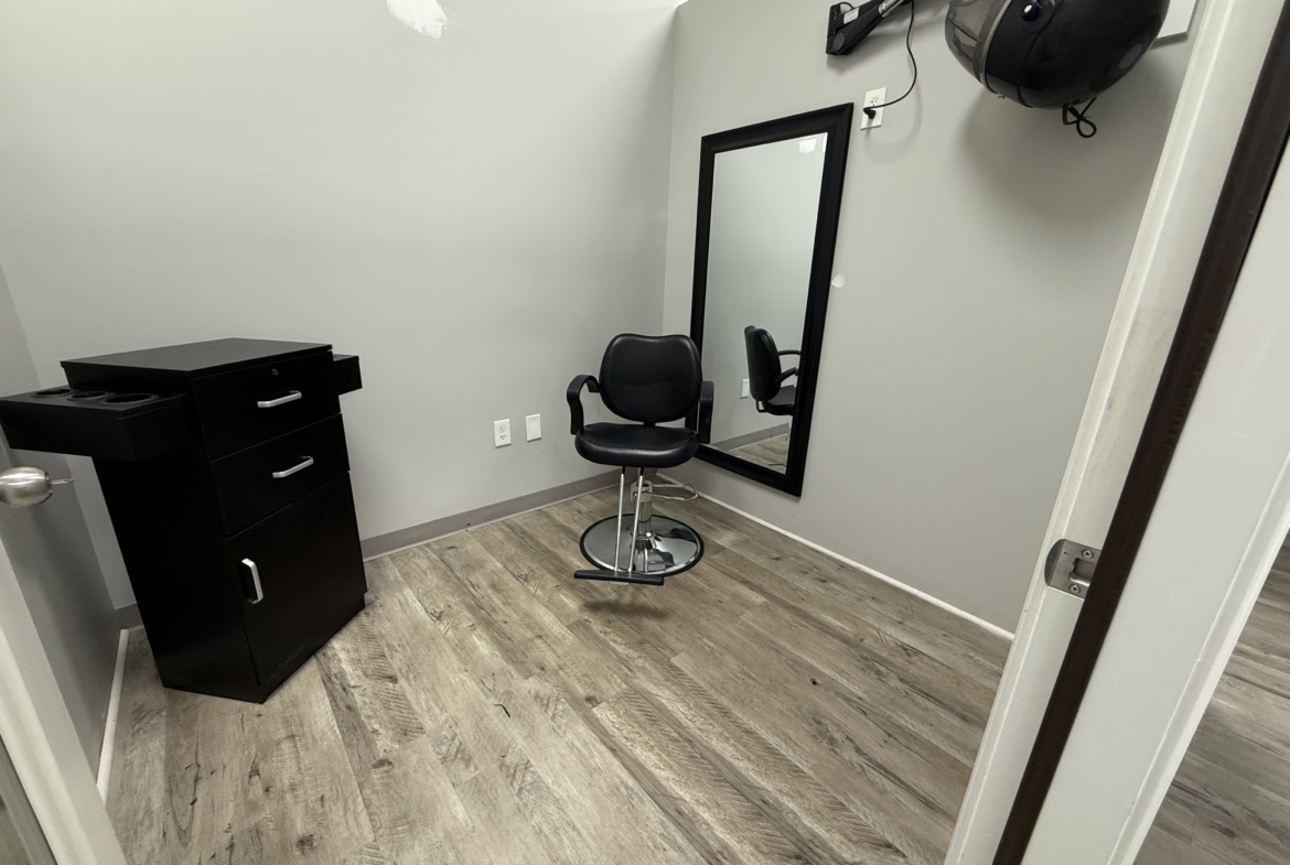 Empty salon rental room with styling chair, mirror, and equipment for hairstylists.