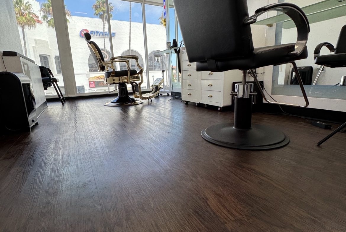 Elegant salon with black styling chairs and natural light from large windows.