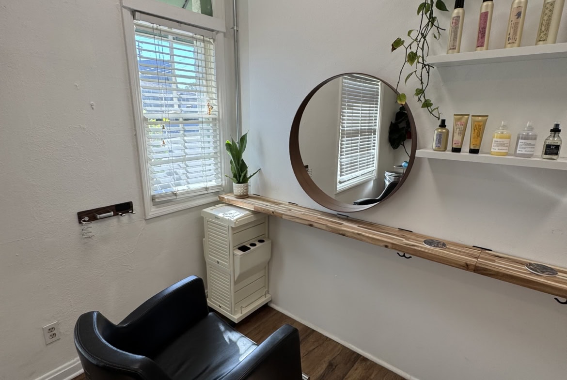 Cozy salon space with chic styling station featuring a mirror and natural light.