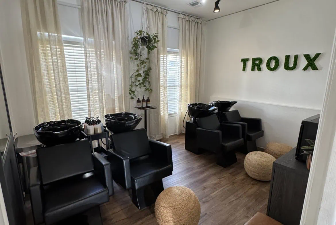 Stylish hair salon with black washing stations, modern seating, natural light, and greenery - perfect for hair and beauty services.
