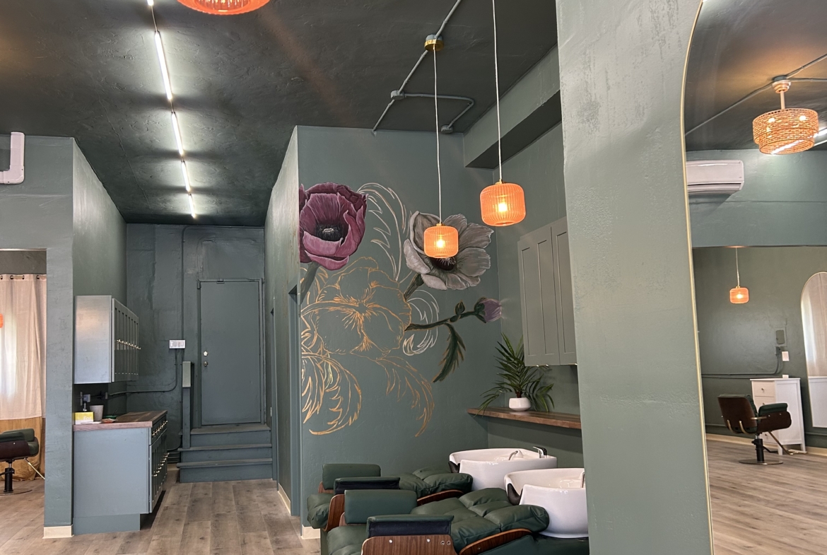 Bright salon space with cozy chairs, wall mural, and warm lighting perfect for hair and beauty treatments.