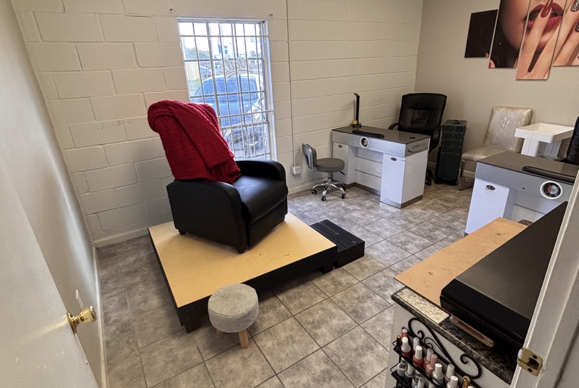 Small salon rental office with manicure station, nail polish display, and cozy seating. Perfect for beauty professionals.