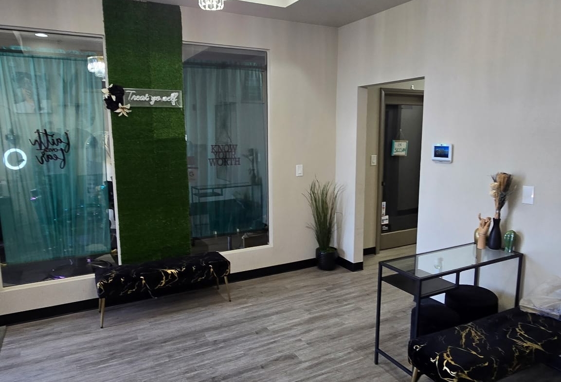 Stylish salon waiting area with elegant chandelier, modern furniture, and decorative plants.