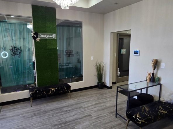 Stylish salon waiting area with elegant chandelier, modern furniture, and decorative plants.