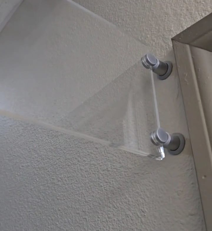 Clear mirror splash guard with metal mounts for bathroom safety.