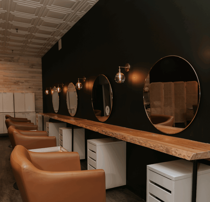 Stylish salon station with mirrors, chairs, and lighting for beauty professionals.