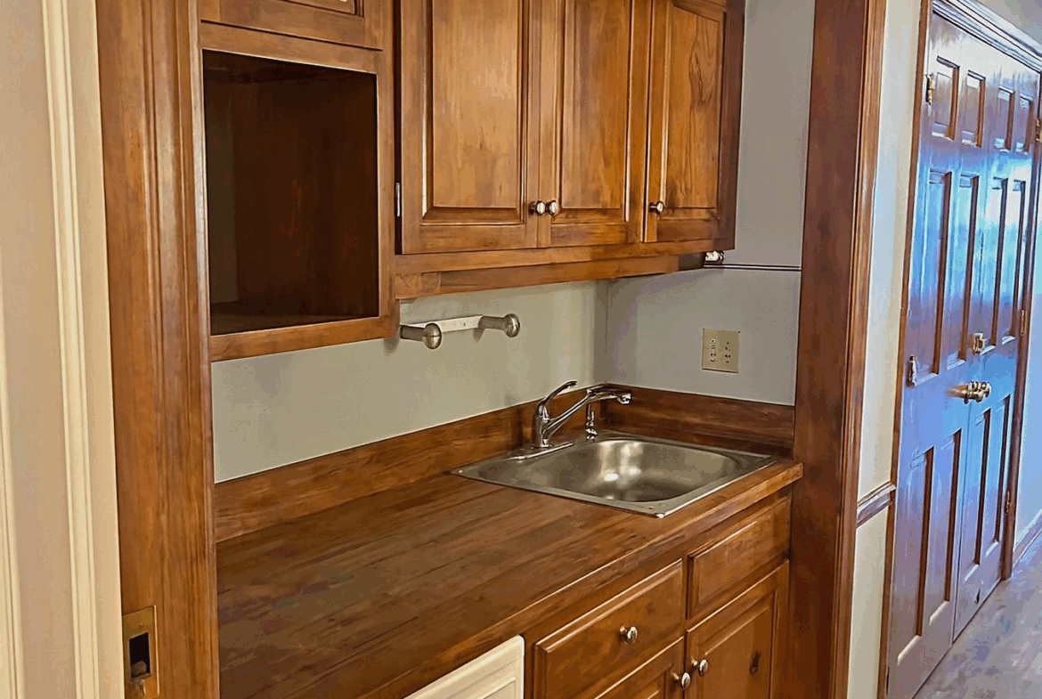 Compact salon kitchenette featuring wooden cabinetry and a stainless steel sink.