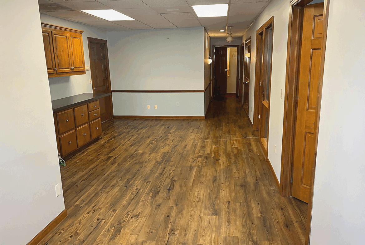 Bright salon interior featuring hardwood floors, wooden cabinets, and multiple doors.