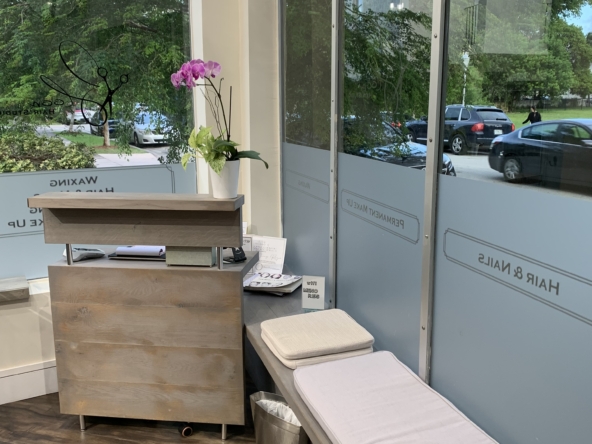 Bright salon reception area with large windows, wooden flooring, and relaxing decor.