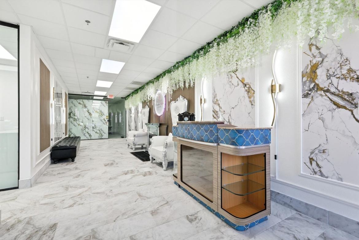 Modern salon waiting area featuring marble walls, stylish seating, and elegant lighting.