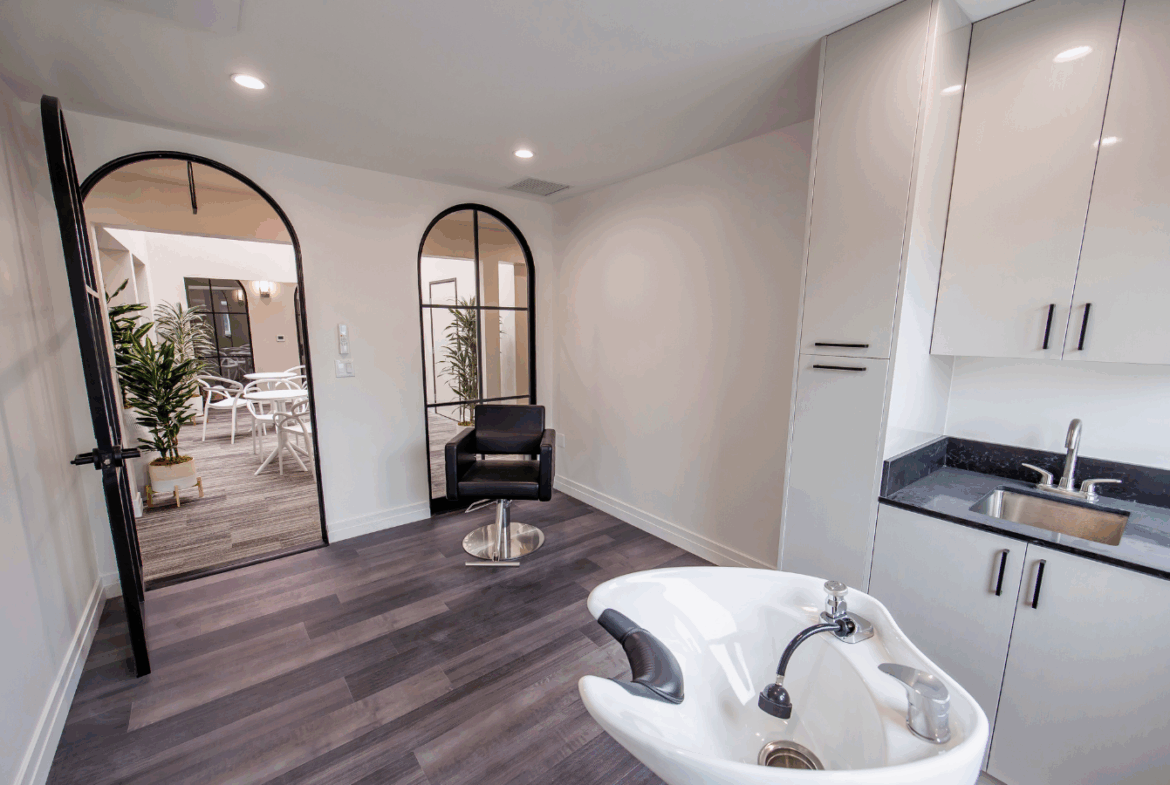 Clean, stylish salon room with styling chair, sink, and kitchen area for salon services.