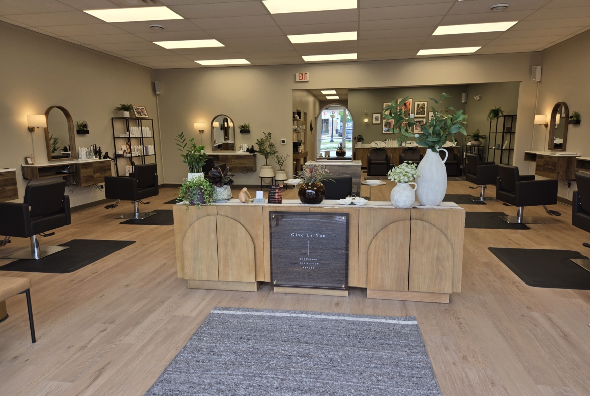 Interior view of a modern, clean hair salon with styling stations and greenery.
