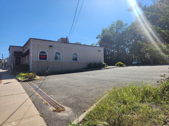 Bright daylight exterior view of a salon business with parking area and green surroundings.