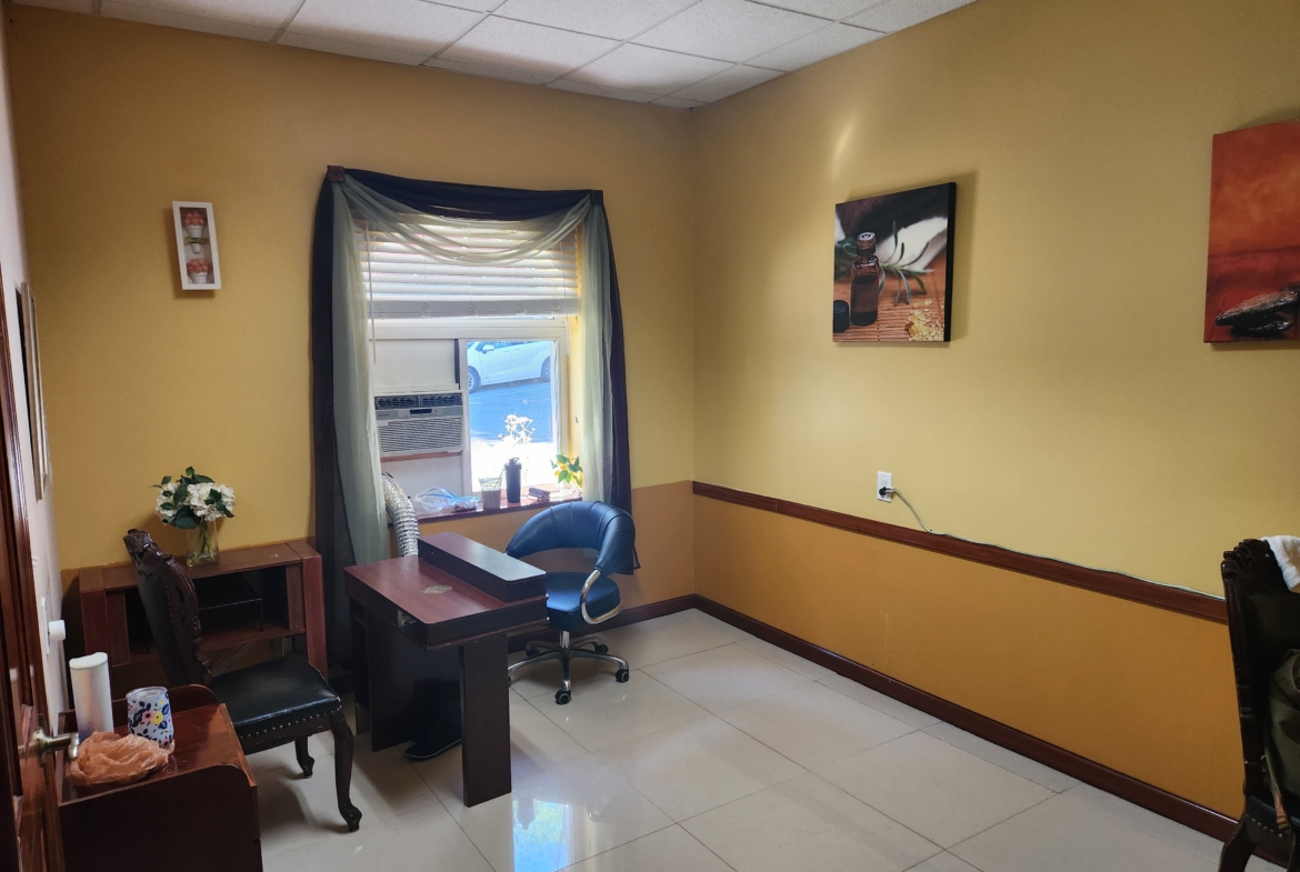 A small, inviting salon or spa room with yellow walls, seating, and decorative accents, offering rental opportunities.