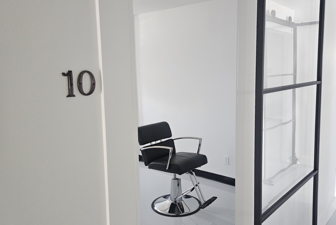 Stylish hair salon workspace featuring a black salon chair and privacy glass divider.