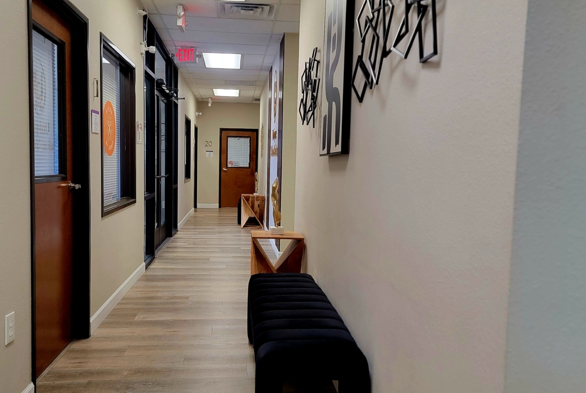Bright salon hallway with stylish wall art, wooden flooring, and seating area.
