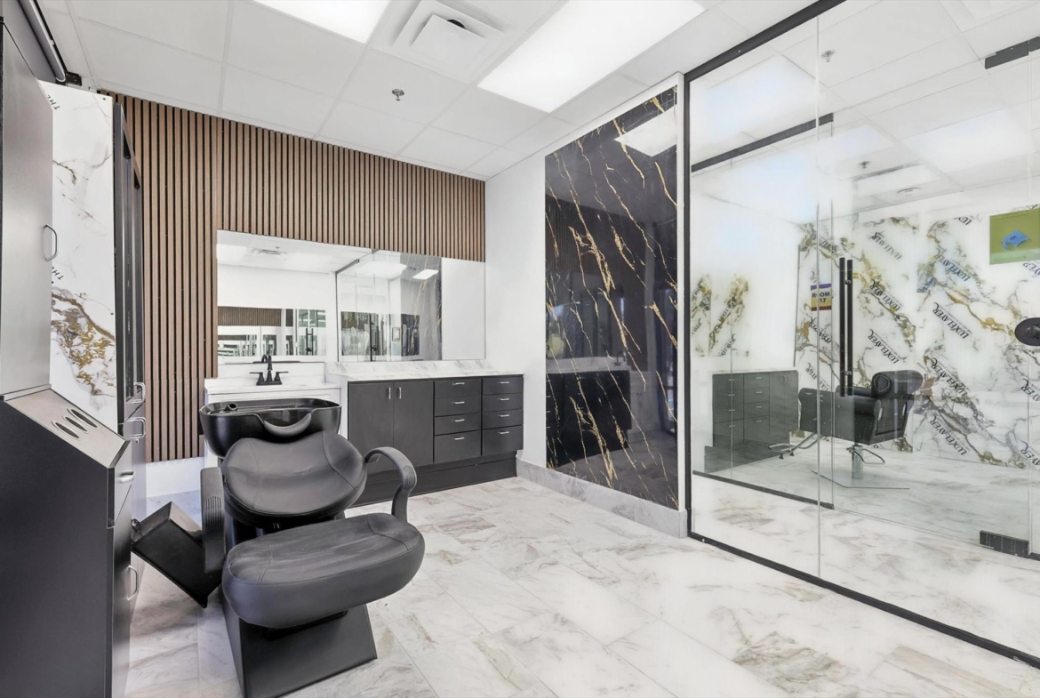 Luxury salon space featuring black marble accents, sleek black furniture, and private styling rooms.