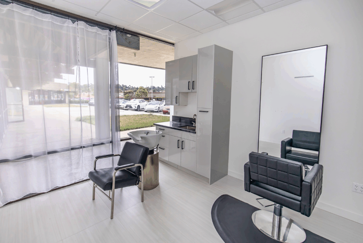 Clean salon space featuring styling chairs and a hair wash station with large windowlight.