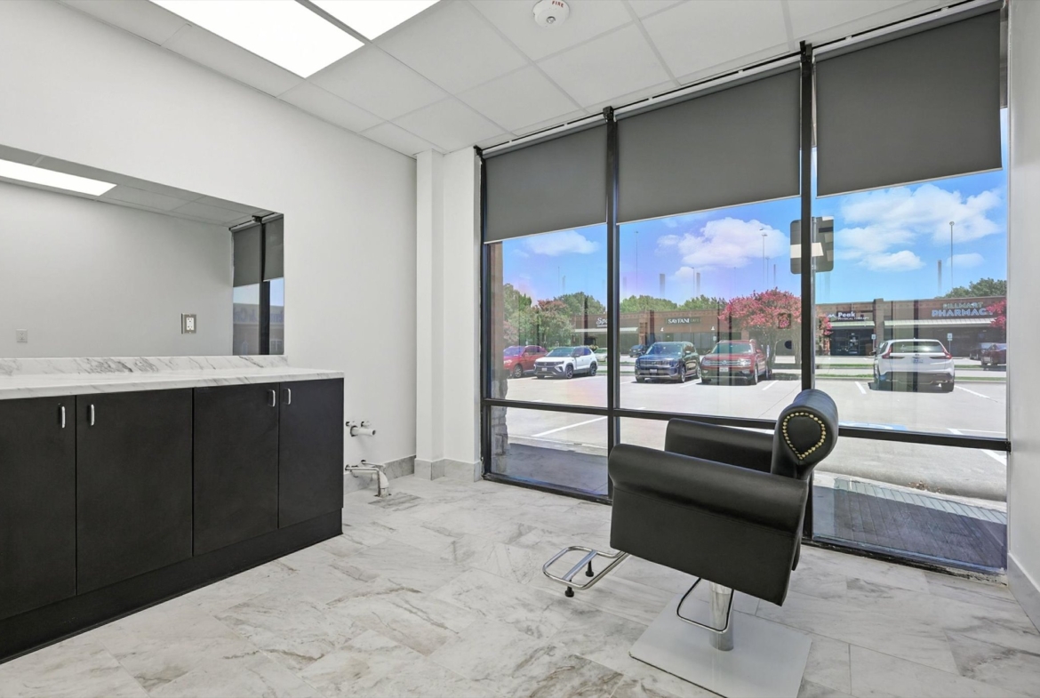 Bright, contemporary hair salon interior with comfortable black styling chair and exterior view.