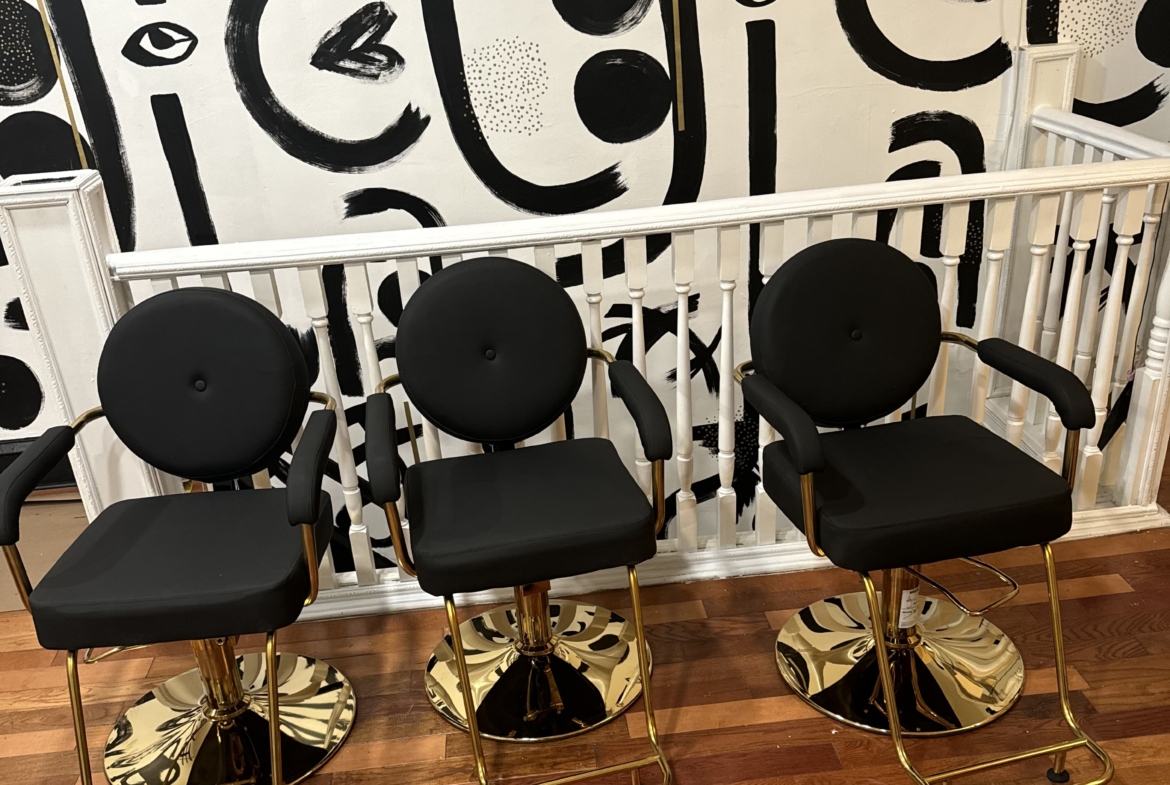 Modern black salon chairs with gold accents in a trendy salon waiting area.