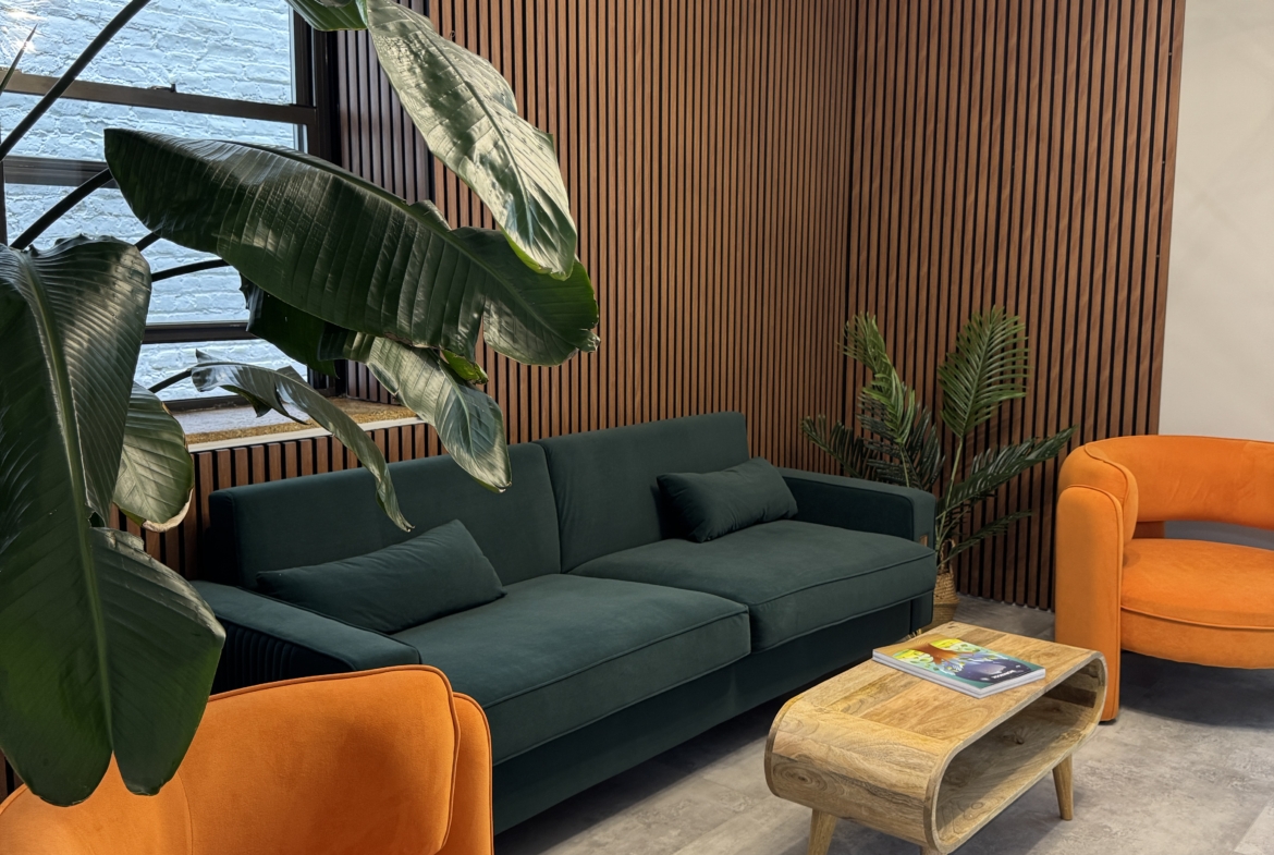 Stylish salon waiting area with orange chairs, green sofa, and wooden wall accents.