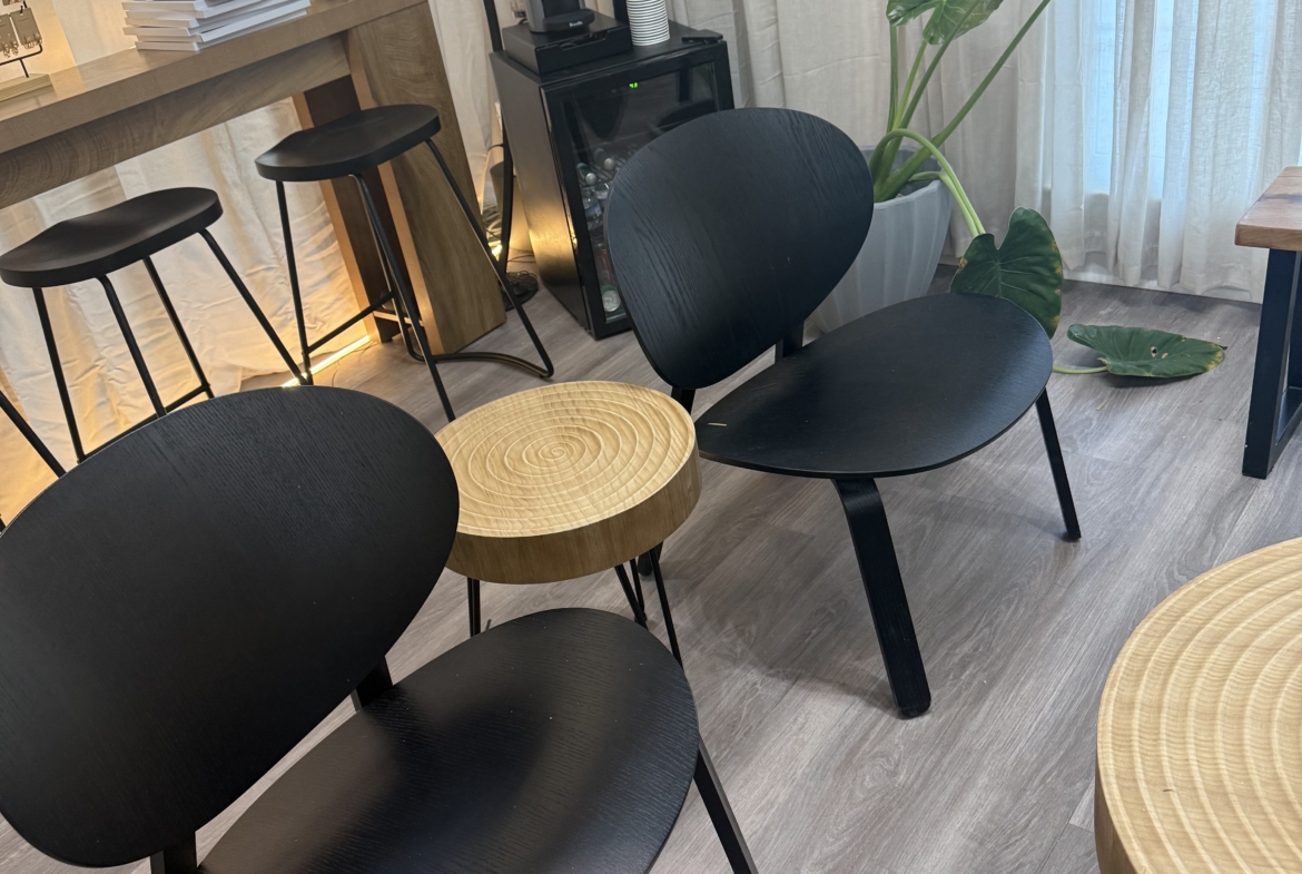 Stylish salon waiting area featuring black chairs, indoor plants, and natural lighting.
