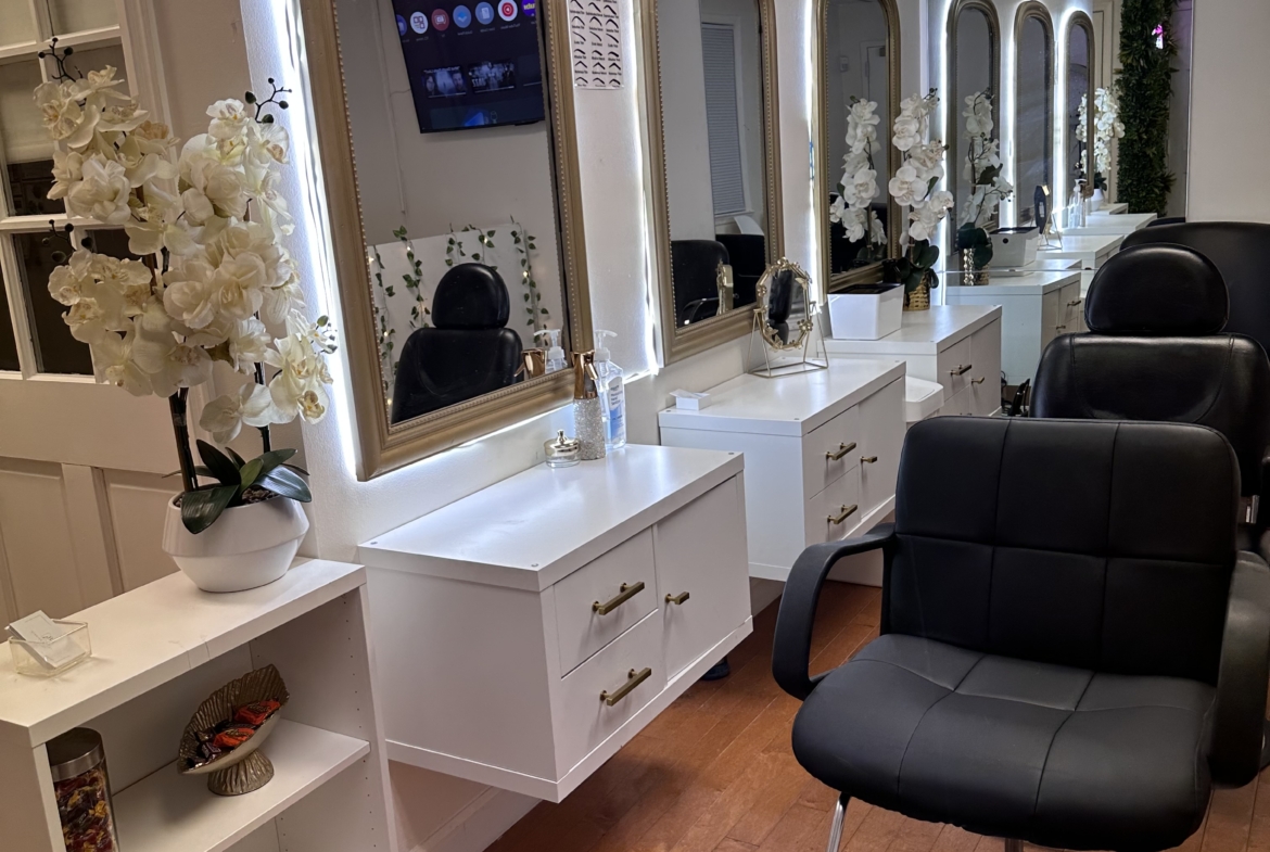 Bright salon styling area with illuminated mirrors and comfortable chairs for clients.