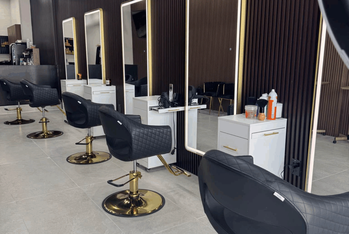 Stylish salon stations featuring black quilted chairs, full-length mirrors, and white storage units for hairdressers.