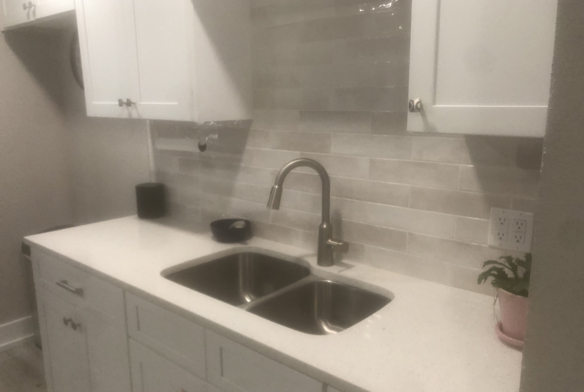 Steel double sink and white cabinetry in a clean salon rental kitchen area.